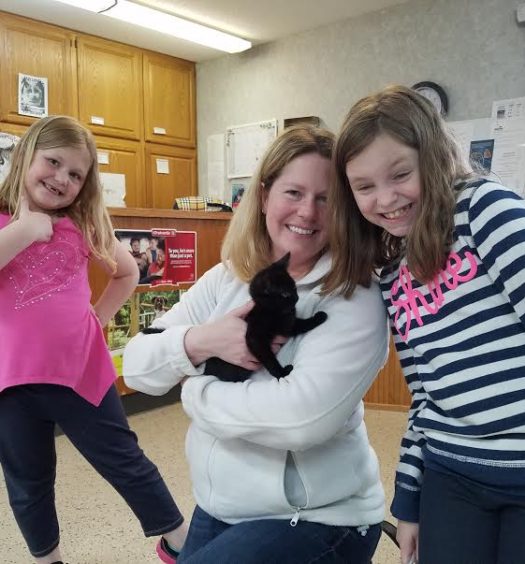 A mom with her two daughters holding a cat