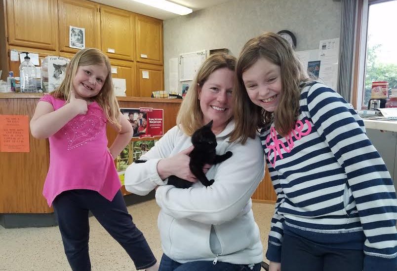 A mom with her two daughters holding a cat