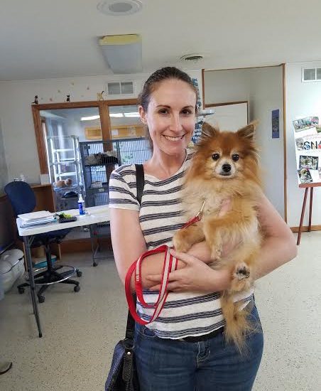A woman holding a small dog in an office.