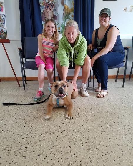 A family of three siting with a dog in the floor