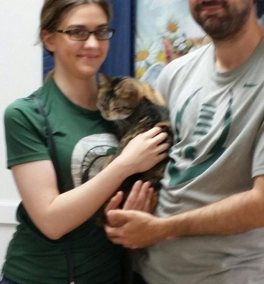 A man and woman holding a cat.
