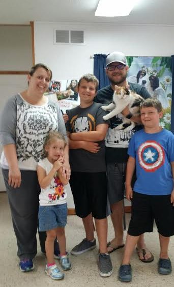 A family posing with a cat in a room.