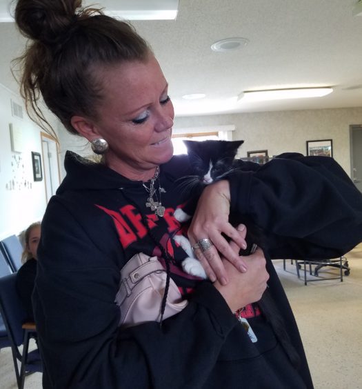 A woman in a black sweatshirt holding a black and white cat.