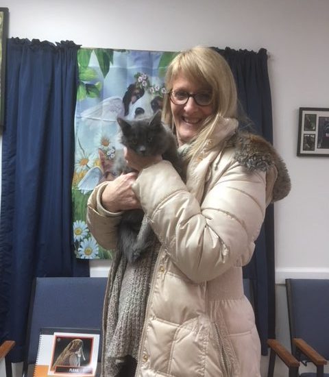 A woman holding a cat in an office.
