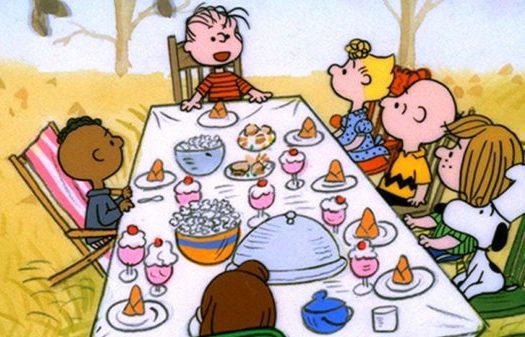 Charlie brown and his friends are sitting around a table.