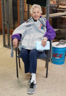 A elder lady sitting on a chair in front of cages