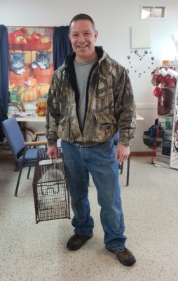 John Monkowski wearing a jacket and holding a dog cage